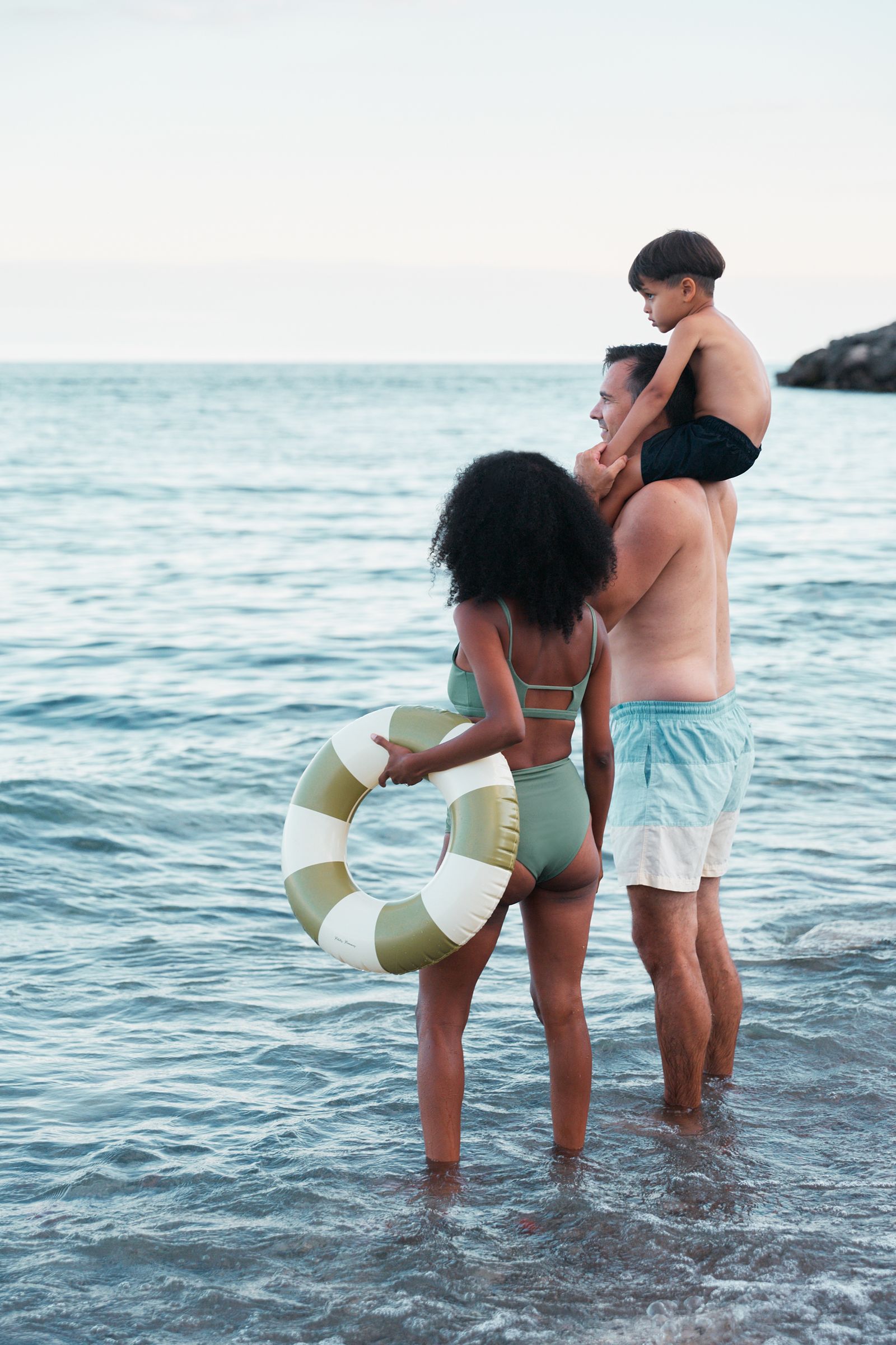 Family wading into Lake Ontario with a striped swim ring